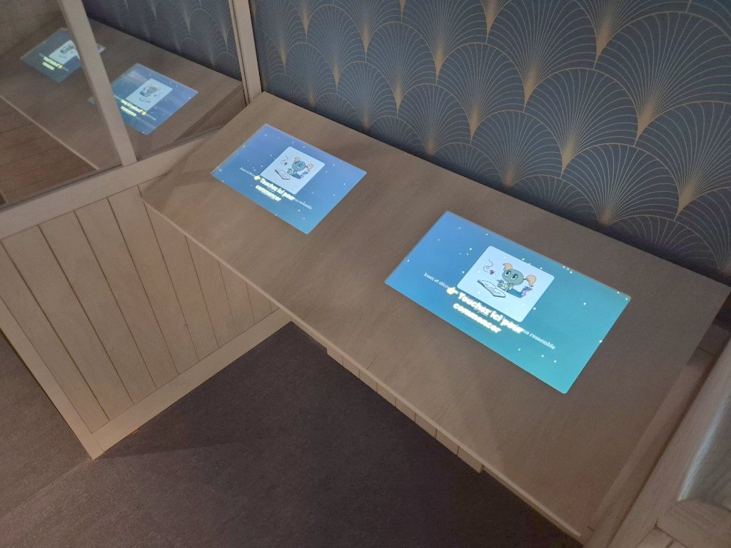 Deux écrans tactiles du quiz encastrés à plat dans le mobilier du musée